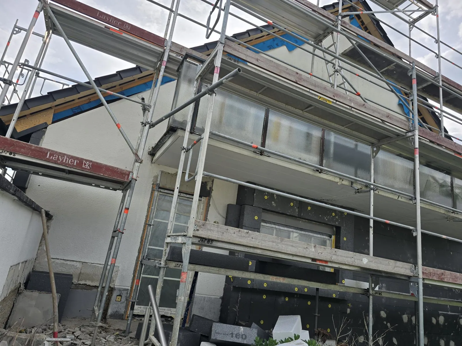 Fassaden- und Dachsanierung mit Gerüst an einem Wohnhaus in Köln.